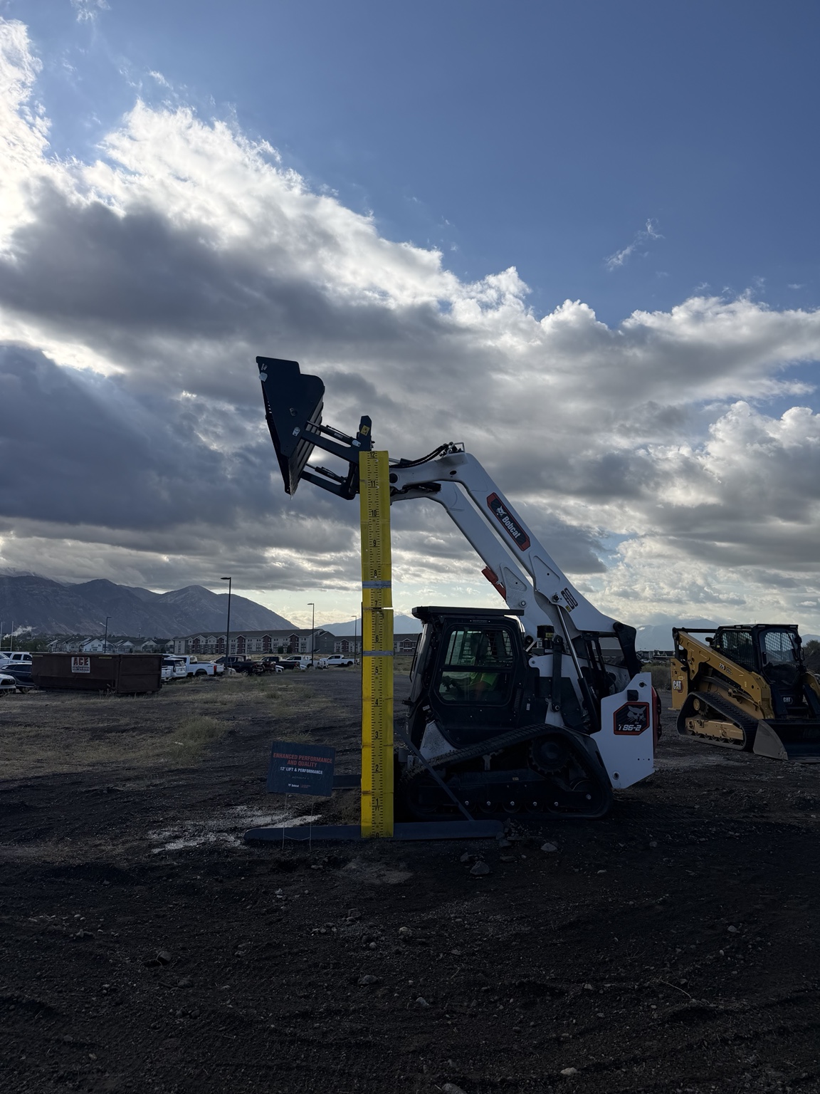Bobcat T86-2 with its bucket raised beside a height marker during loader training.
